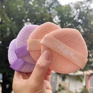 Close-up view of soft pink and purple makeup sponge puffs with finger ribbons for easy use.