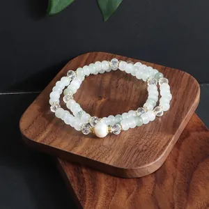 Close-up of a double-layered beaded bracelet with a central pearl and crystals
