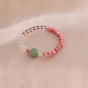 Detailaufnahme eines Kristallarmbands mit rosa Perlen und grünem Achat auf Seide