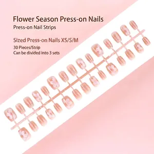 Lot de 30 faux ongles roses à fleurs avec dégradé et détails scintillants.