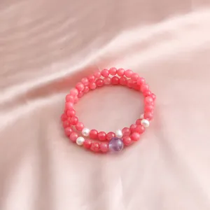 Detail view of a double-layer pink gemstone bracelet with pearls on silk background.
