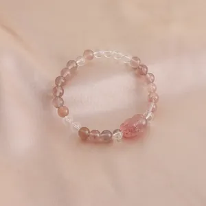 Detailed view of a natural strawberry quartz bracelet with a carved Pixiu charm