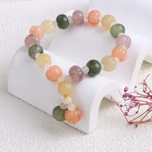 Nahaufnahme eines bunten Jade-Armbands mit fein geschnitzten Perlen in Kürbisform.
