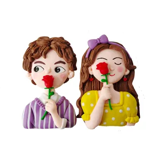 Close-up of cute cartoon couple figurines holding red roses for Valentine's Day cake decoration