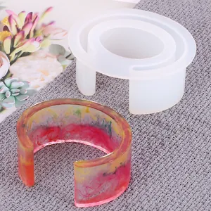 Detail view of a C-shaped silicone bracelet mold with a colorful resin sample.