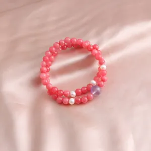 Detailed macro shot of a double-strand pink beaded bracelet with white pearl accents