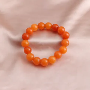 Detailansicht des leuchtend orangen Sonnenstein-Perlenarmbands auf elegantem Satinstoff