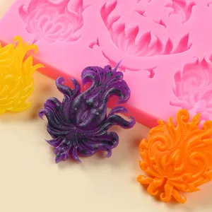 Dettaglio di stampo in silicone rosa con decorazioni floreali colorate in fondente.