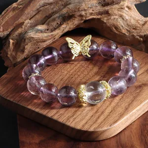 Close-up detail of a natural 12mm amethyst bead bracelet featuring a gold butterfly charm
