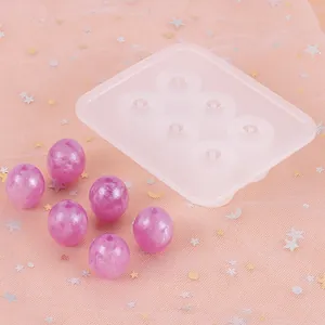 Detailweergave van een 6-gaats siliconen mal voor hars met paarse kralen op roze gaas.