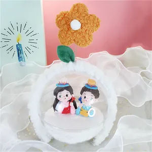 Detalle de diadema de flores con adorables figuras de arcilla y una flor naranja suave