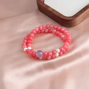 Close-up detail of double-layer pink jade beads bracelet with pearl accents on silk.