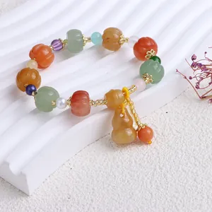 Detailansicht eines Jade-Armbands mit Kürbisperlen und einem Flaschenkürbis-Anhänger.