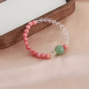 Nahaufnahme eines Naturkristall-Armbands mit rosa Steinen und grüner Kürbis-Achatperle