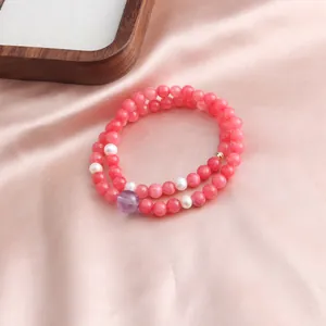 Detail view of a double strand pink jade bracelet featuring white pearls and amethyst bead