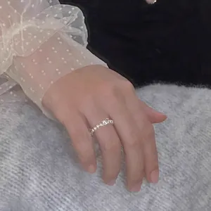 Gedetailleerde close-up van een elegante witte parelring met vierkant kristal op de hand