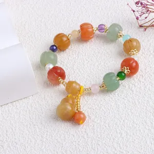 Detailansicht eines Armbands aus natürlichen, bunten Jadegrasperlen und Kürbis-Charm.
