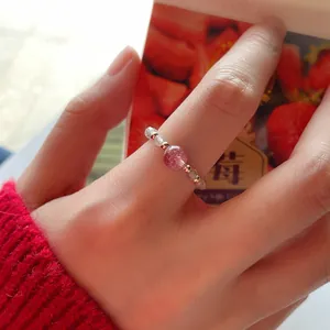Detail view of a handmade natural strawberry quartz and moonstone beaded ring on a finger.