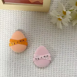 Macro view of soft peach and pink teardrop makeup sponges featuring decorative ribbons