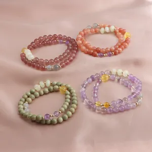 Detailed view of four double-loop beaded bracelets in strawberry quartz, sunstone, and amethyst.