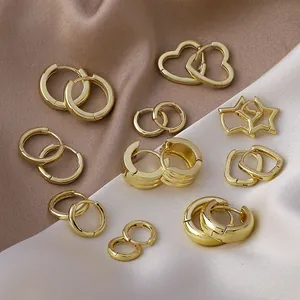 Detailed close-up view of various geometric gold hoop earrings on luxury soft satin fabric