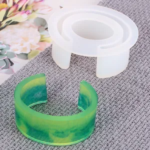 Close-up of C-shaped silicone bracelet mold and finished marbled resin jewelry piece
