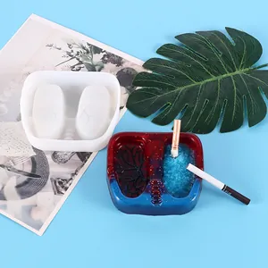 Close-up of lung shaped silicone mold and finished resin ashtray on blue background