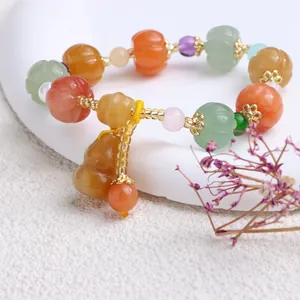 Makrodetail eines Jade-Armbands im Ethno-Stil mit Kürbisperlen und Kürbisanhänger.