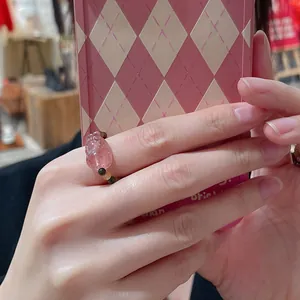 Detailed macro view of a natural pink crystal beaded ring worn on a finger.