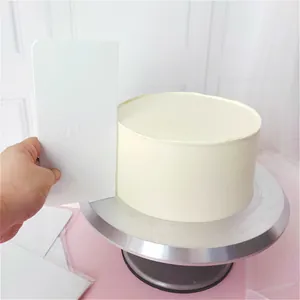 Primer plano de un raspador de tartas de plástico ABS blanco alisando crema en un pastel