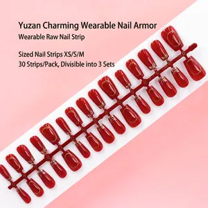 Detailed view of red press-on nails on a strip with elegant gold line patterns