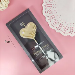Detailansicht einer goldenen herzförmigen Love-Geburtstagskerze in eleganter Verpackung