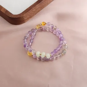 Detail of double-strand amethyst and sunstone beaded bracelet on pink silk fabric
