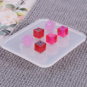 Detail van vierkante siliconen mal met uitgeharde glitterharsblokjes in roze en rood