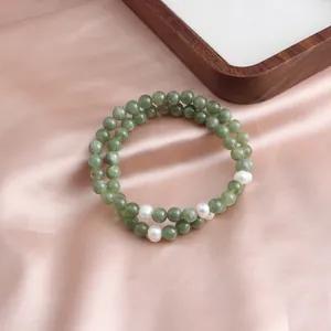 Close-up detail of a double-strand green jade bead bracelet featuring white pearl accents