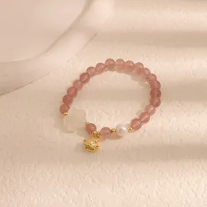 Dettaglio del bracciale con perline rosa con ciondolo a fiore e perla