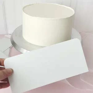 Vista detallada de una rasqueta rectangular de ABS blanca para alisar crema de pasteles