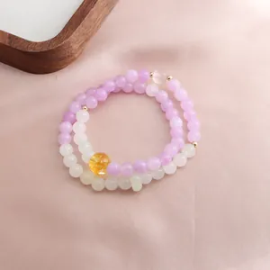 Detail shot of double-layer purple kunzite and yellow crystal beaded bracelet on pink silk