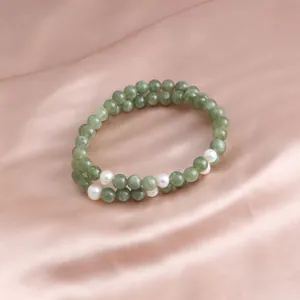 Close-up of a double-strand green jade bracelet with pearls on pink silk.
