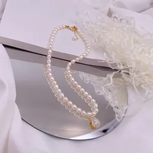 Detailaufnahme einer Süßwasser-Reisperlenkette mit Tropfen-Zirkonia-Anhänger auf Spiegel