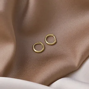 Elegant minimalist small gold hoop earrings displayed on premium champagne satin fabric