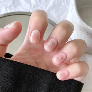 Close-up of pink blush press-on nails with silver star details and glossy finish