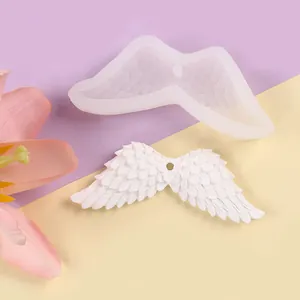 A detailed view showing a silicone mold for angel wings next to a finished white plaster cast.