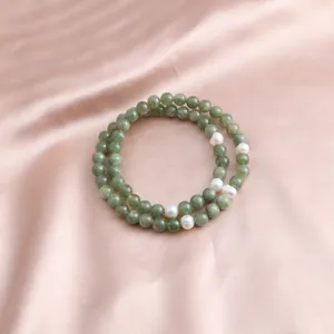 Macro view of double-strand natural jade and pearl bracelet on elegant silk fabric