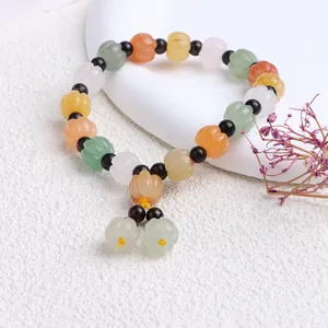 Makro-Detail eines natürlichen Jinsi-Jade-Armbands mit bunten Kürbisperlen im Ethno-Stil.