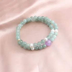 Detailed macro view of a double-strand jade and pearl bracelet on pink satin.