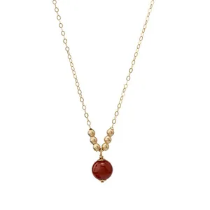Dettaglio di una collana in oro 14K con pendente a sfera in corniola rossa naturale