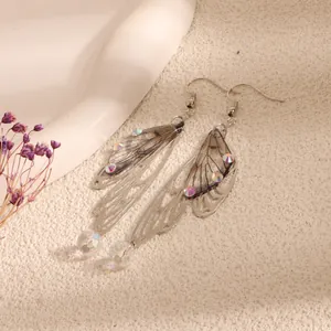 Macro detail of elegant silver-tone cicada wing earrings with iridescent rhinestones