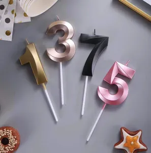 Detail shot of number birthday candles 1, 3, 7, 5 in metallic gold, black, and pink