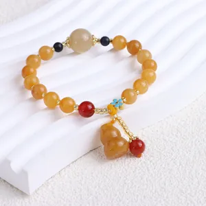 Nahaufnahme eines Perlenarmbandes aus Xinjiang-Goldsid-Jade mit einem Naturbutterkürbis-Anhänger.